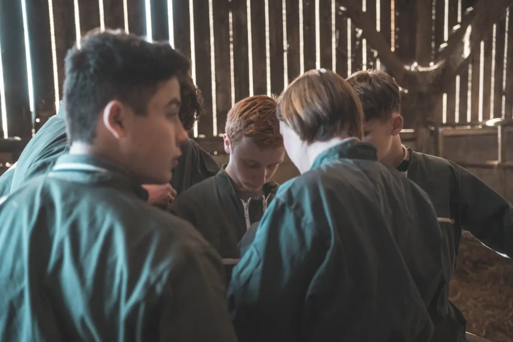 Groupe d'élèves de 1re Bac Pro CGEA en combinaison, réunis dans une grange en bois